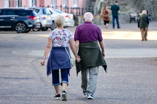 An older couple walking outdoors together, holding hands