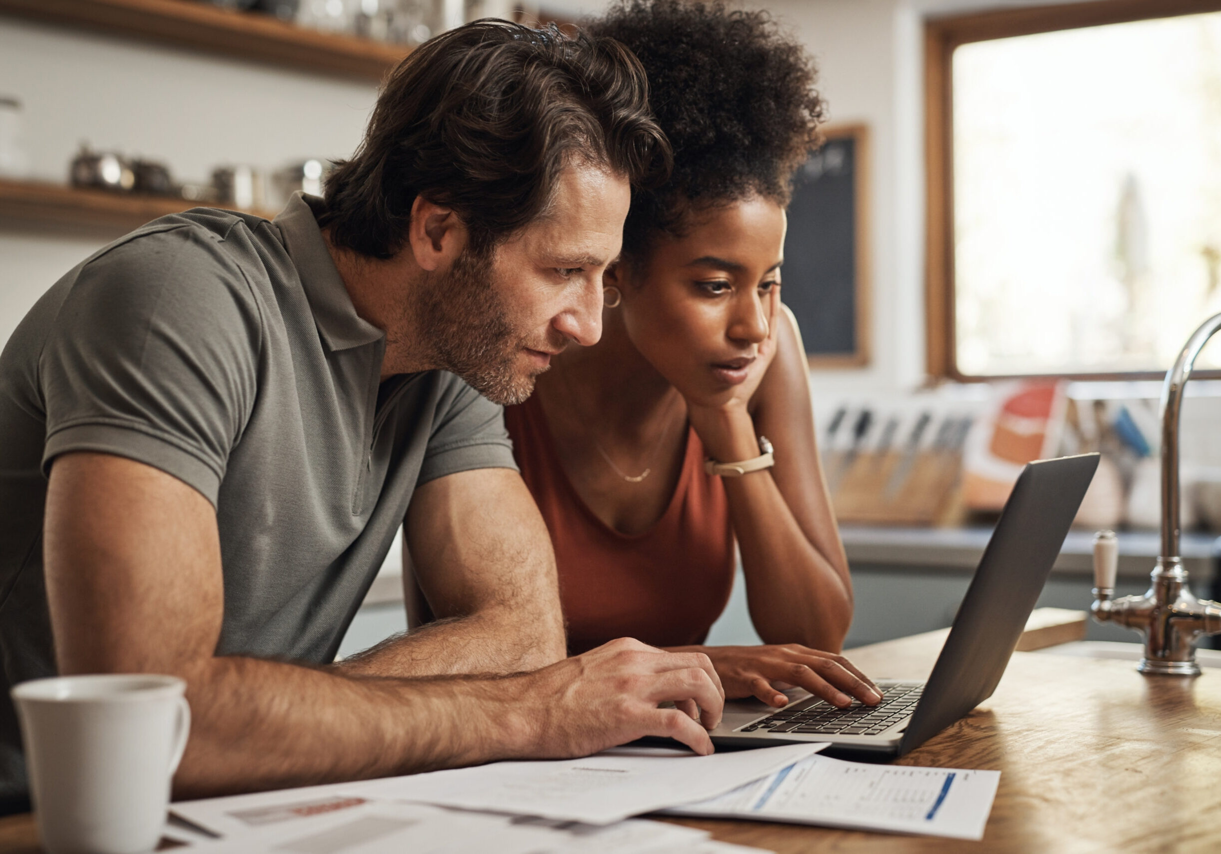 Cropped shot of a couple using their laptop and going through paperwork at home